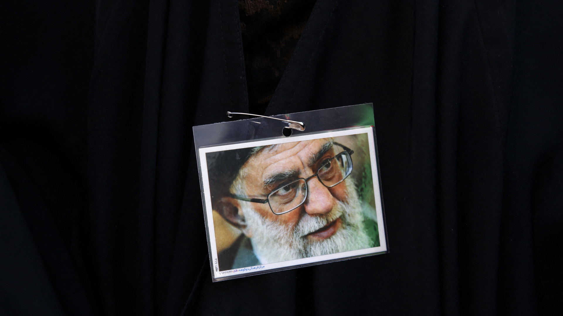 An Iranian pro-government protester wears a pin with a portrait of Supreme Leader Ayatollah Ali Khamenei during a rally against the recent anti-government protests, in Tehran, on 25 September (AFP)