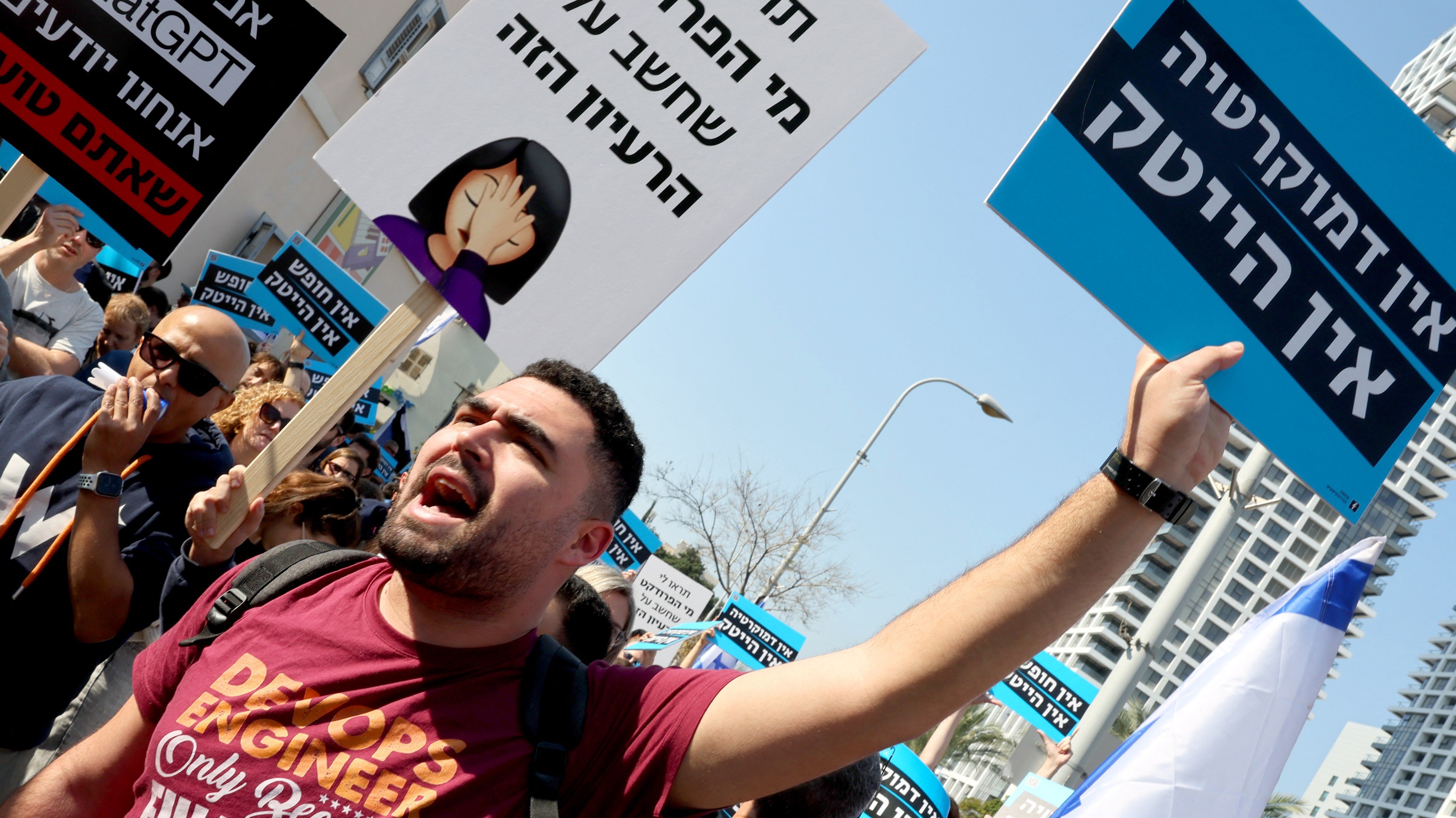 High-tech company workers block a road and lift placards as they strike for an hour in Israel's coastal city of Tel Aviv, on 24 January 2023, to protest the Israeli government's controversial plans to overhaul the judicial system.