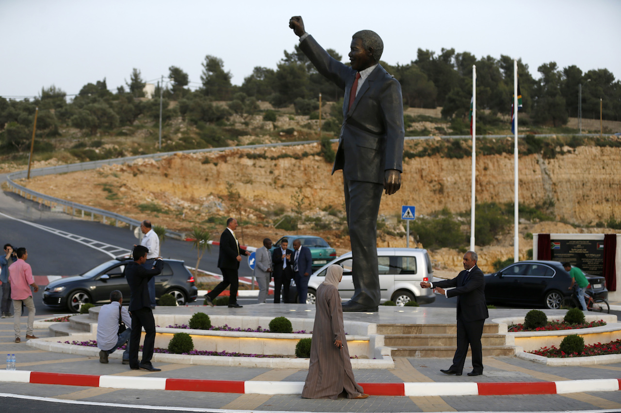 Palestinians stand next to a giant statue of Nelson Mandela following its inauguration ceremony in the West Bank city of Ramallah (AFP)