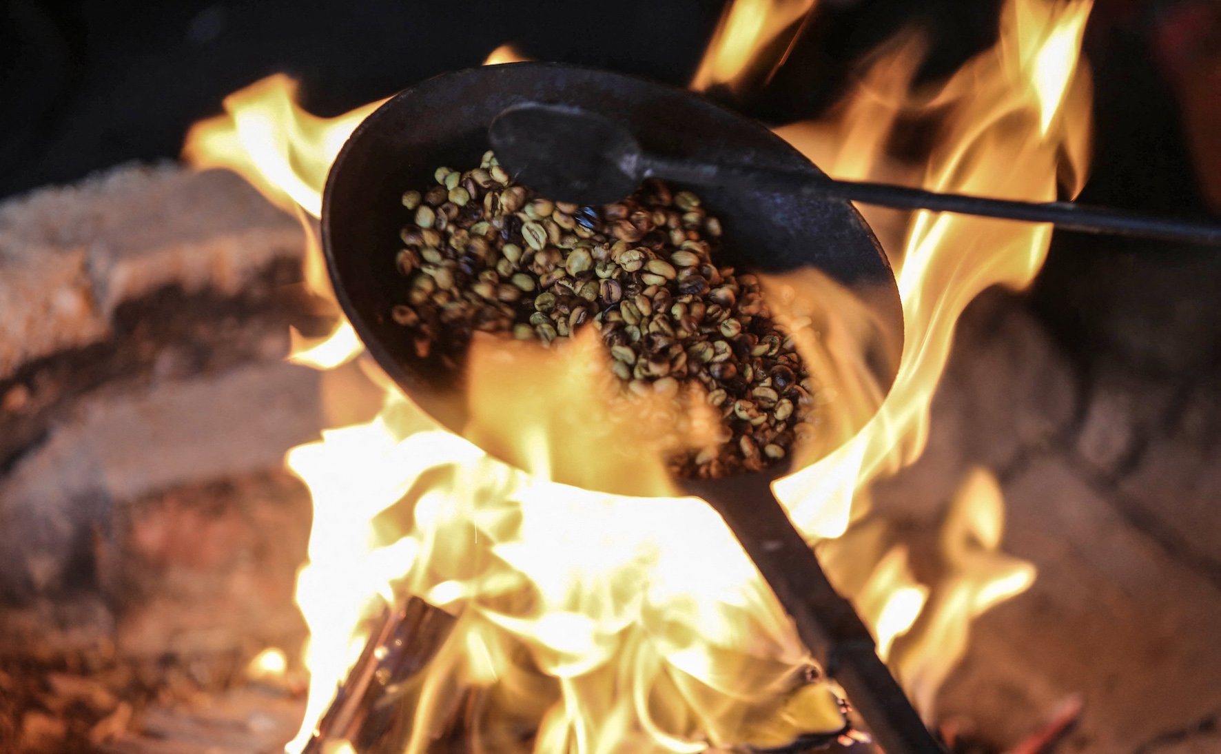 Raw green coffee beans roasted on a pan (AFP/ Amer Almohibany)