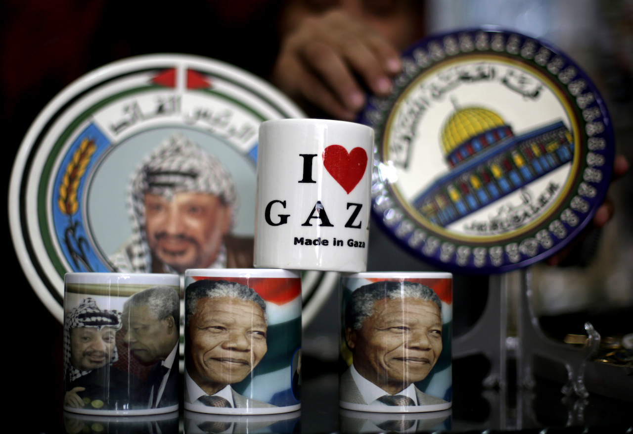 A vendor displays cups bearing the portrait of late South African former president Nelson Mandela and late Palestinian leader Yasser Arafat (L) in Gaza City (AFP)