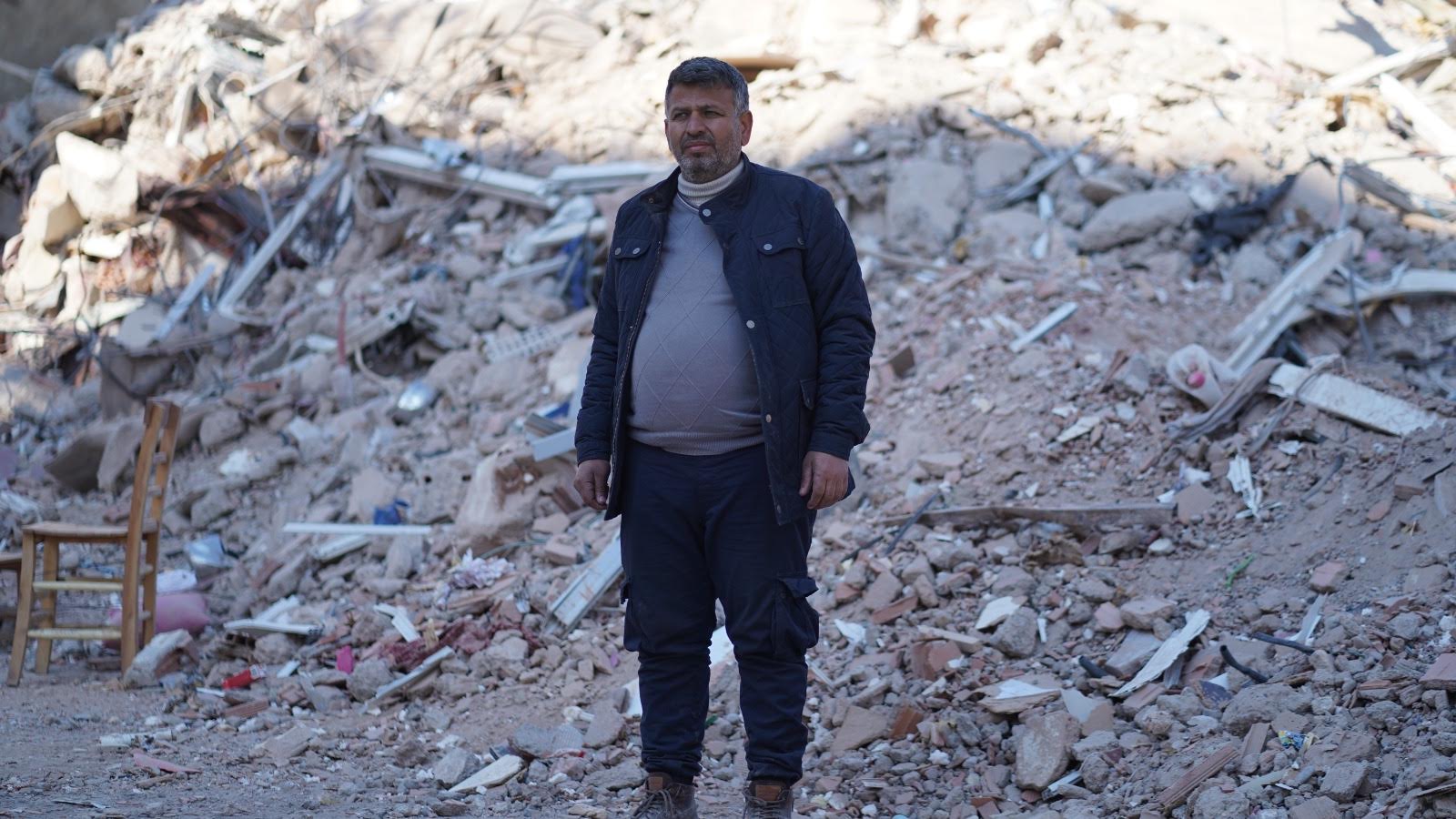 Yusuf Turan stands amid the rubble of his neighbourhood (MEE/Muhammed Masso)