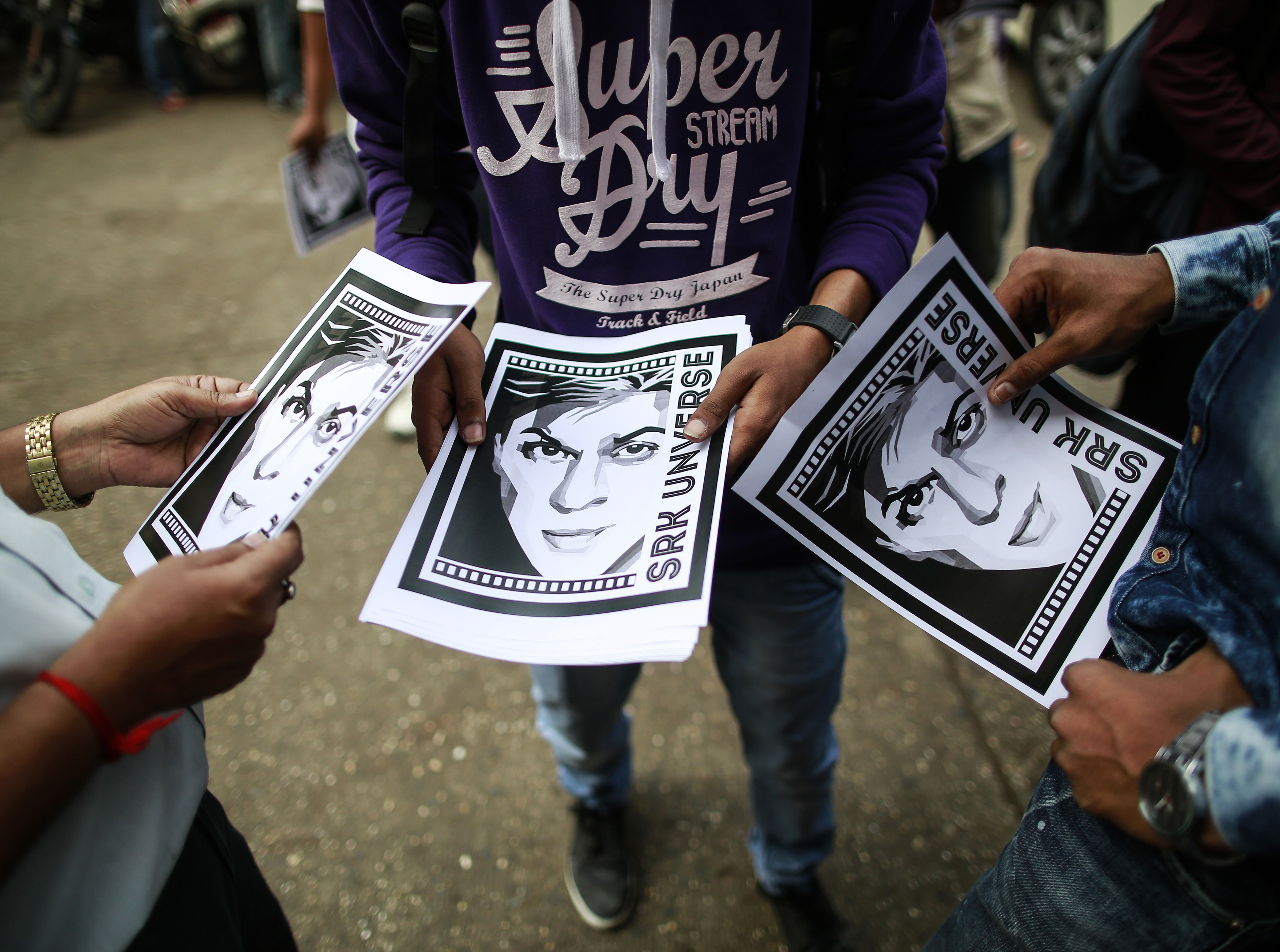 Cinema goers hold posters of actor Shah Rukh Khan (Reuters)
