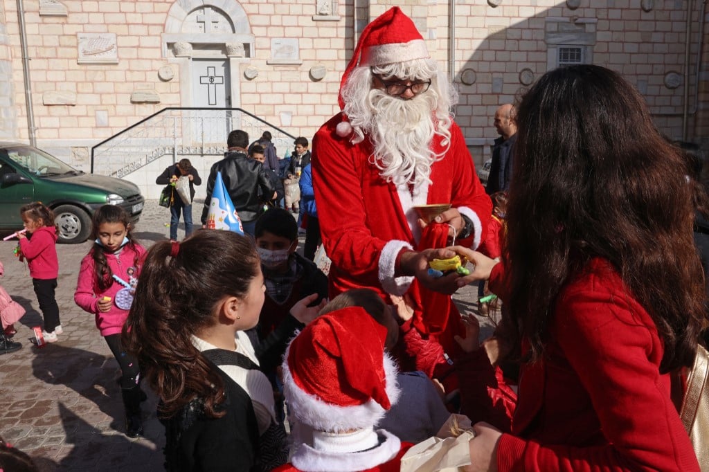 Un homme habillé en Père Noël distribue des cadeaux à Gaza (AFP/Mohammed Abed)