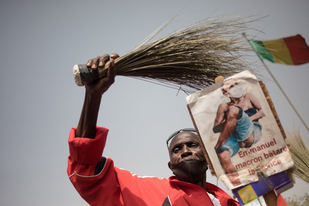 A protester holds a broom and a caricature of President Macron during a demonstration to celebrate France's announcement to withdraw French troops from Mali, in Bamako, 19 February 2022