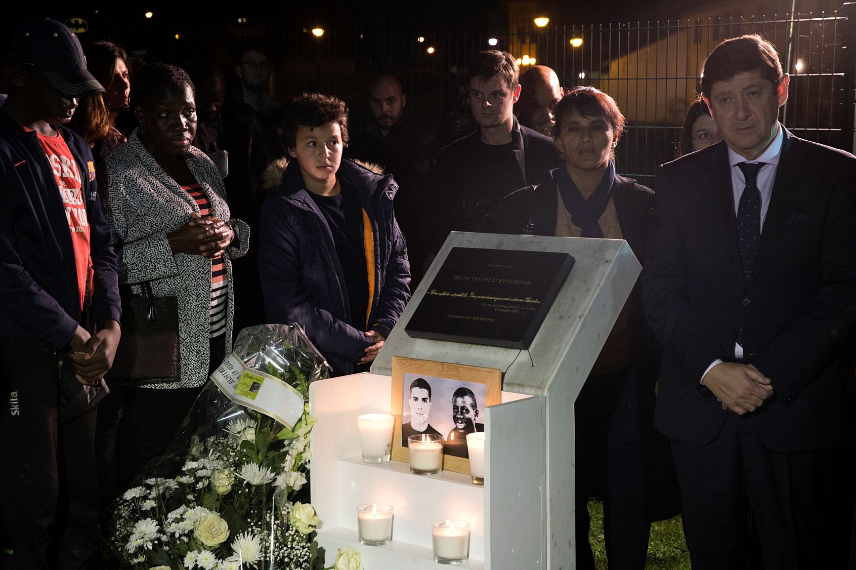 Le sénateur et ministre de la Jeunesse de l’époque Patrick Kanner (à droite) se tient près d’une plaque à la mémoire de Zyed Benna et Bouna Traoré, deux adolescents morts en fuyant la police (AFP)