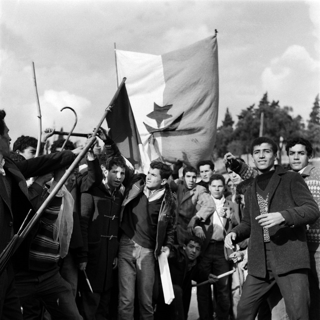 Des milliers d’Algériens armés de bâtons et brandissant le drapeau du FLN descendent vers les quartiers européens d’Alger le 11 décembre 1960 (AFP)