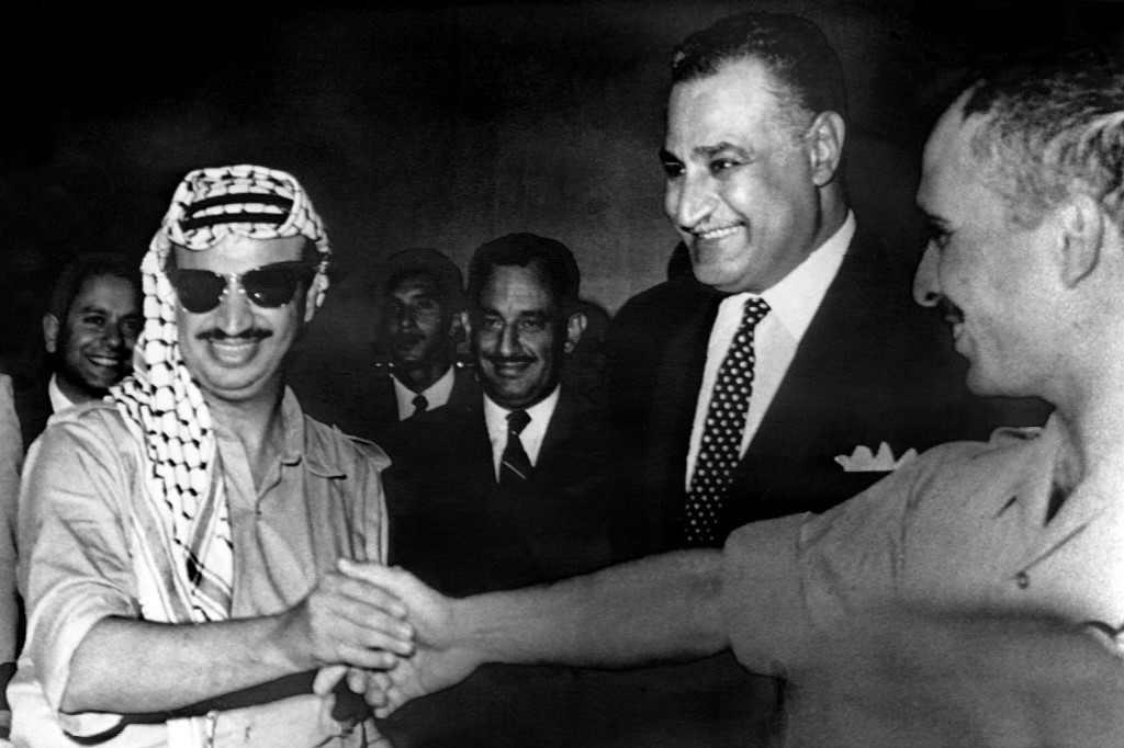 Le chef de l’OLP Yasser Arafat (à gauche) et le roi Hussein de Jordanie (à droite) se serrent la main sous le regard de Nasser (au centre), le 27 septembre 1970 au Caire, après avoir signé un accord de cessez-le-feu lors des événements de Septembre noir (AFP)