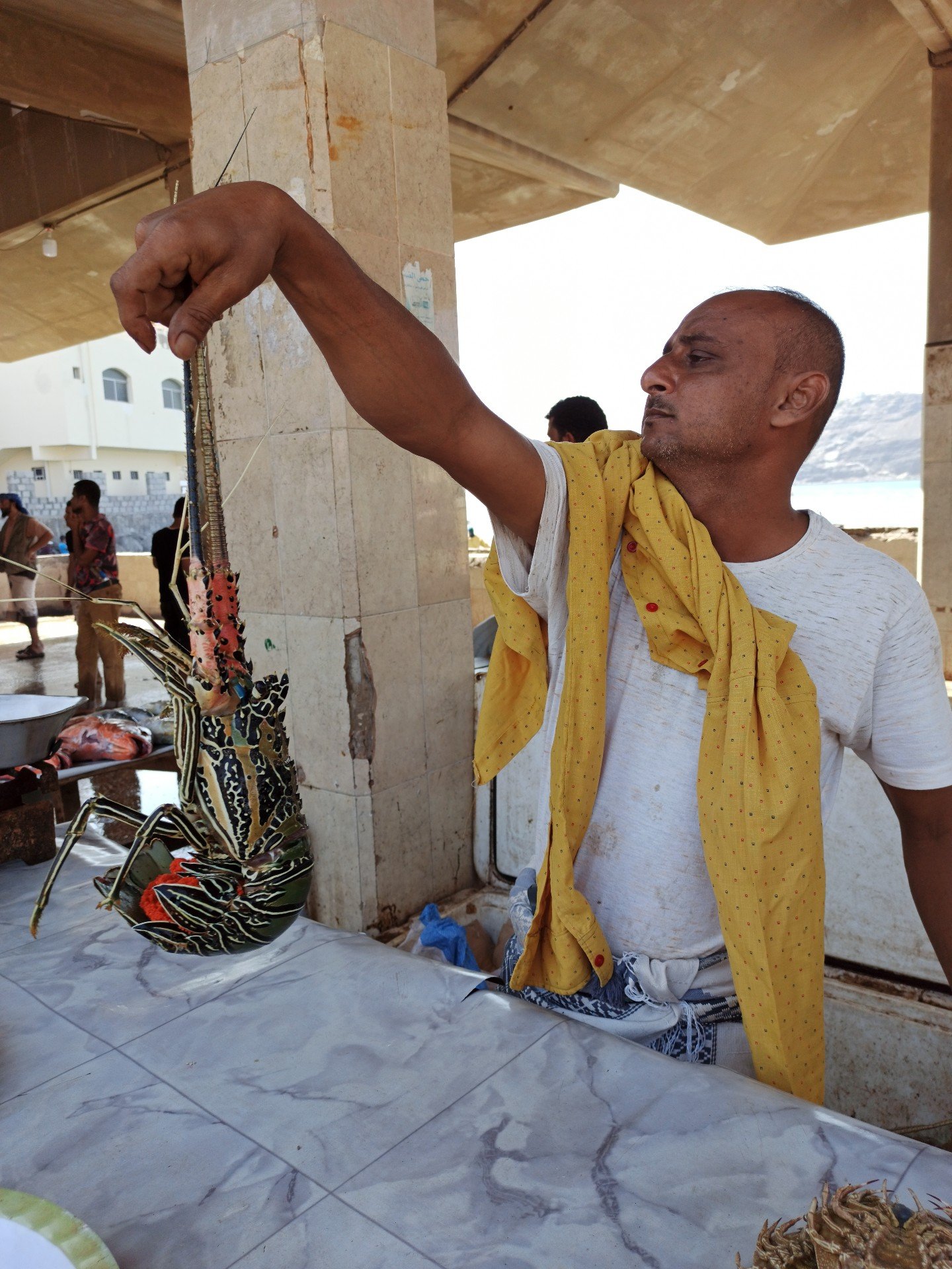 Un pêcheur vend un homard à Sirah, dans la province d’Aden, dans le sud du Yémen (MEE)