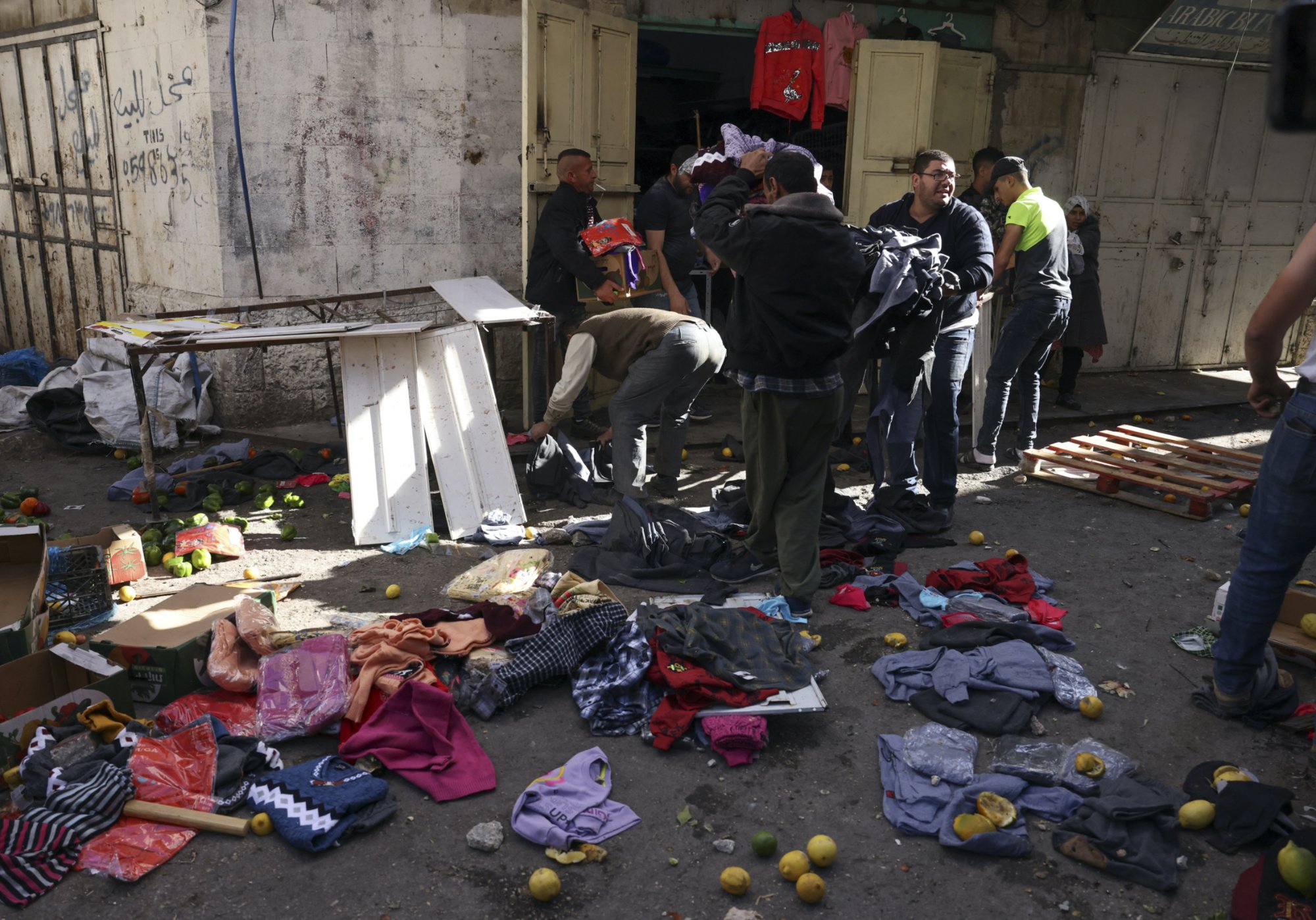 Palestinian shop owners salvage their merchandise at a market, ransacked by marching Jewish settlers in Hebron (AFP)