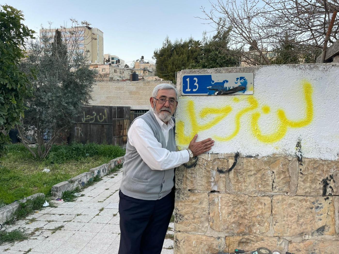 Nabil al-Kurd se tient à côté d’un mur recouvert d’un graffiti affirmant « nous ne partirons pas » en arabe (MEE/Aseel Jundi)