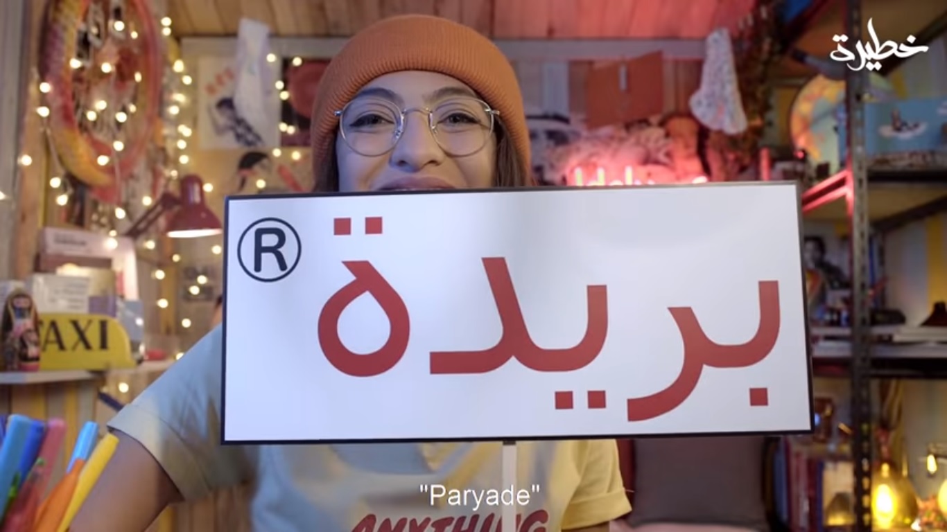 Maria holds up a sign reading "to period" in Arabic (screengrab)