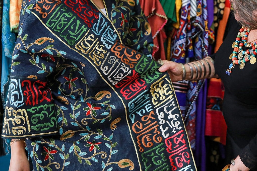 A Franco-Iraqi fashion designer residing in Jordan shows off a dress which displays the Thuluth script of calligraphy (AFP)