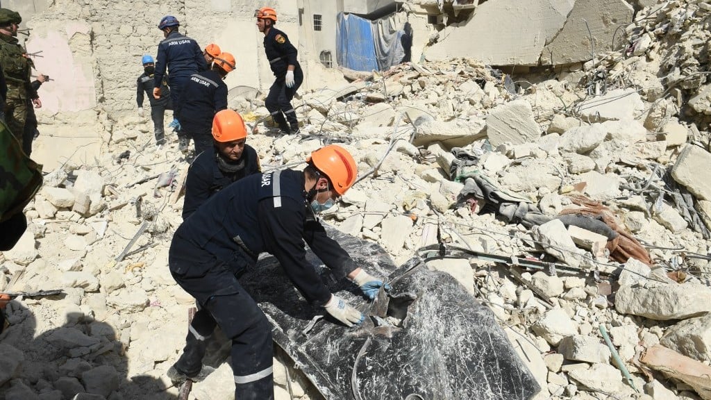 Armenian rescuers sift through the rubble of a collapsed building in Aleppo, Syria, on 9 February 2023 (AFP)