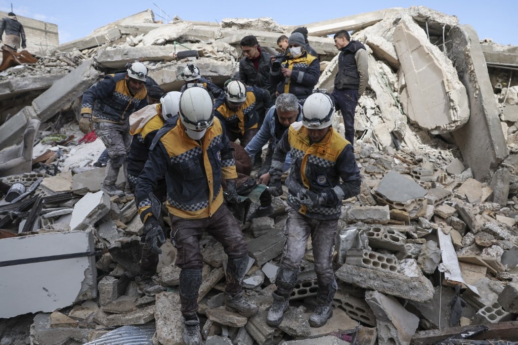 Des membres de la défense civile syrienne, connus sous le nom de Casques blancs, sortent une victime des décombres en Syrie (AFP)