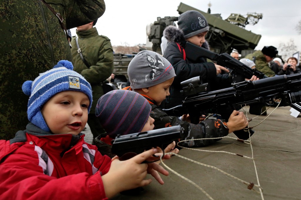 Des enfants manipulent de véritables armes non chargées lors d’une campagne de promotion du service dans l’armée russe à Sébastopol, en Crimée, le 20 décembre 2014 (AFP)
