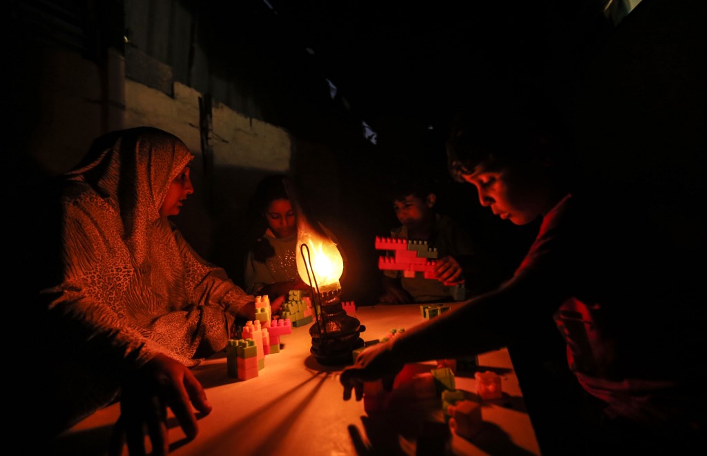 A Palestinian woman uses a gas lamp during a power cut in Gaza's Khan Younis refugee camp in July 2018 (AFP)