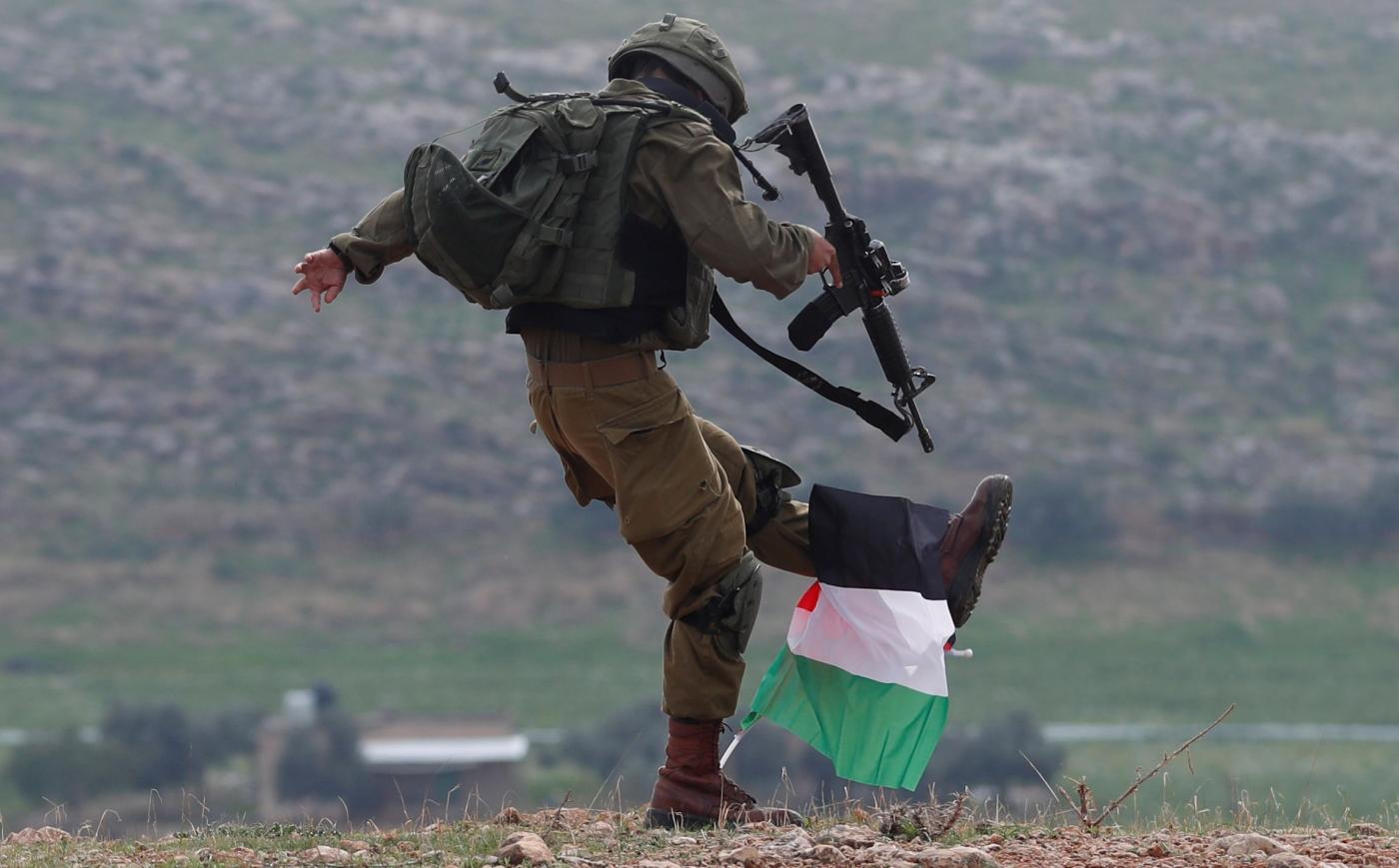 An Israeli soldier kicks a Palestinian flag during a protest against US President Donald Trump’s Middle East ‘peace plan’ in the occupied West Bank on 29 January (Reuters)