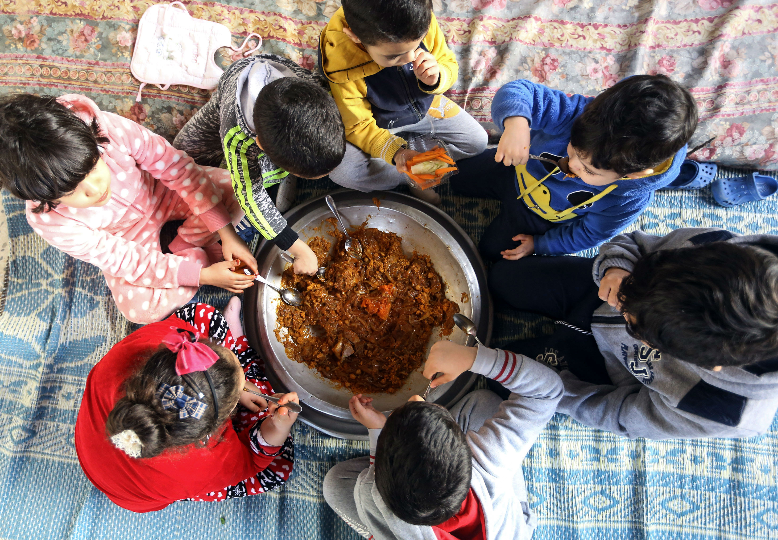 Libyan children preparing to eat freshly cooked couscous with lamb and onions in Tripoli in February 2018 (AFP)
