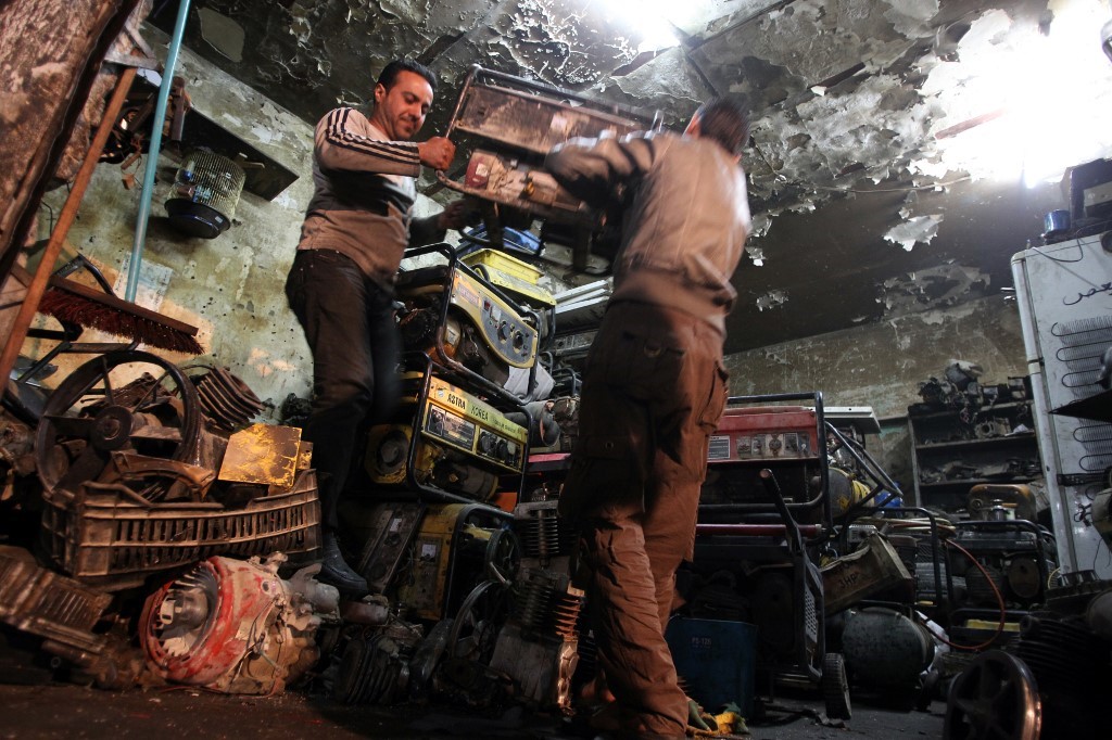 Iraqi men carry a diesel generator, which are often bought by individuals to supply electricity to their homes due to frequent power cuts, at their shop in the capital Baghdad on March 19, 2014. 