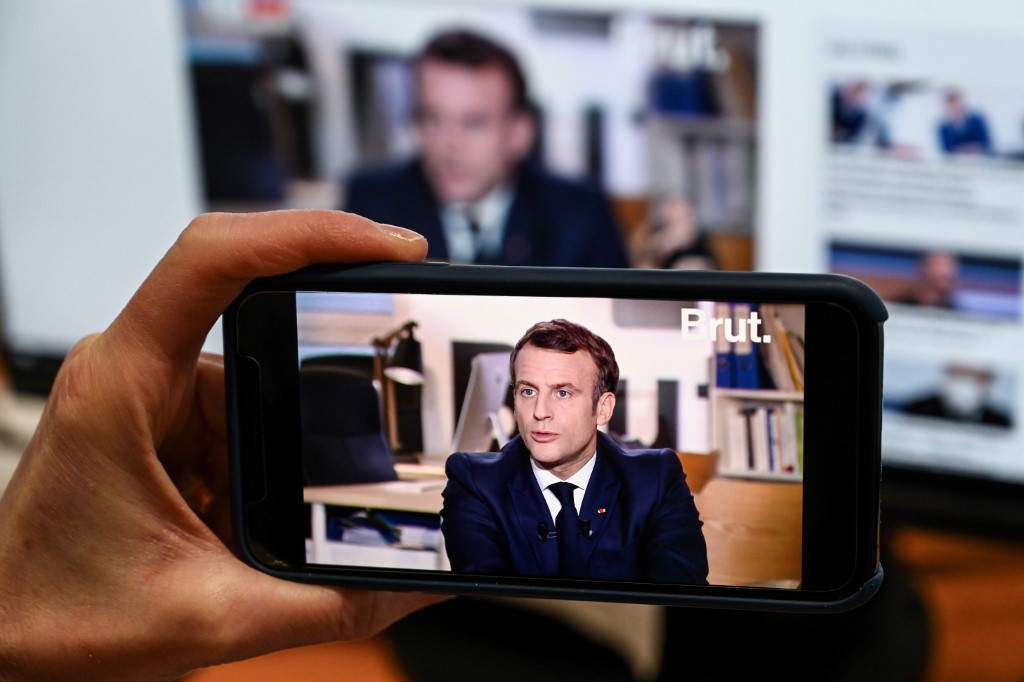 A journalist watches an interview with French President Emmanuel Macron in Paris on 4 December (AFP)