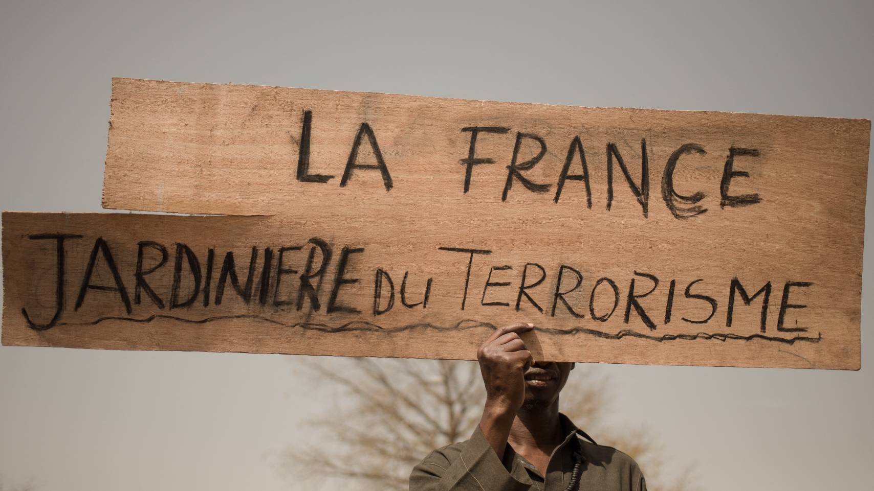 A protester holds a placard reading "France, gardener of terrorism" during a demonstration organised by the pan-Africanst platform Yerewolo to celebrate France's announcement to withdraw French troops from Mali, in Bamako, on February 19, 2022.