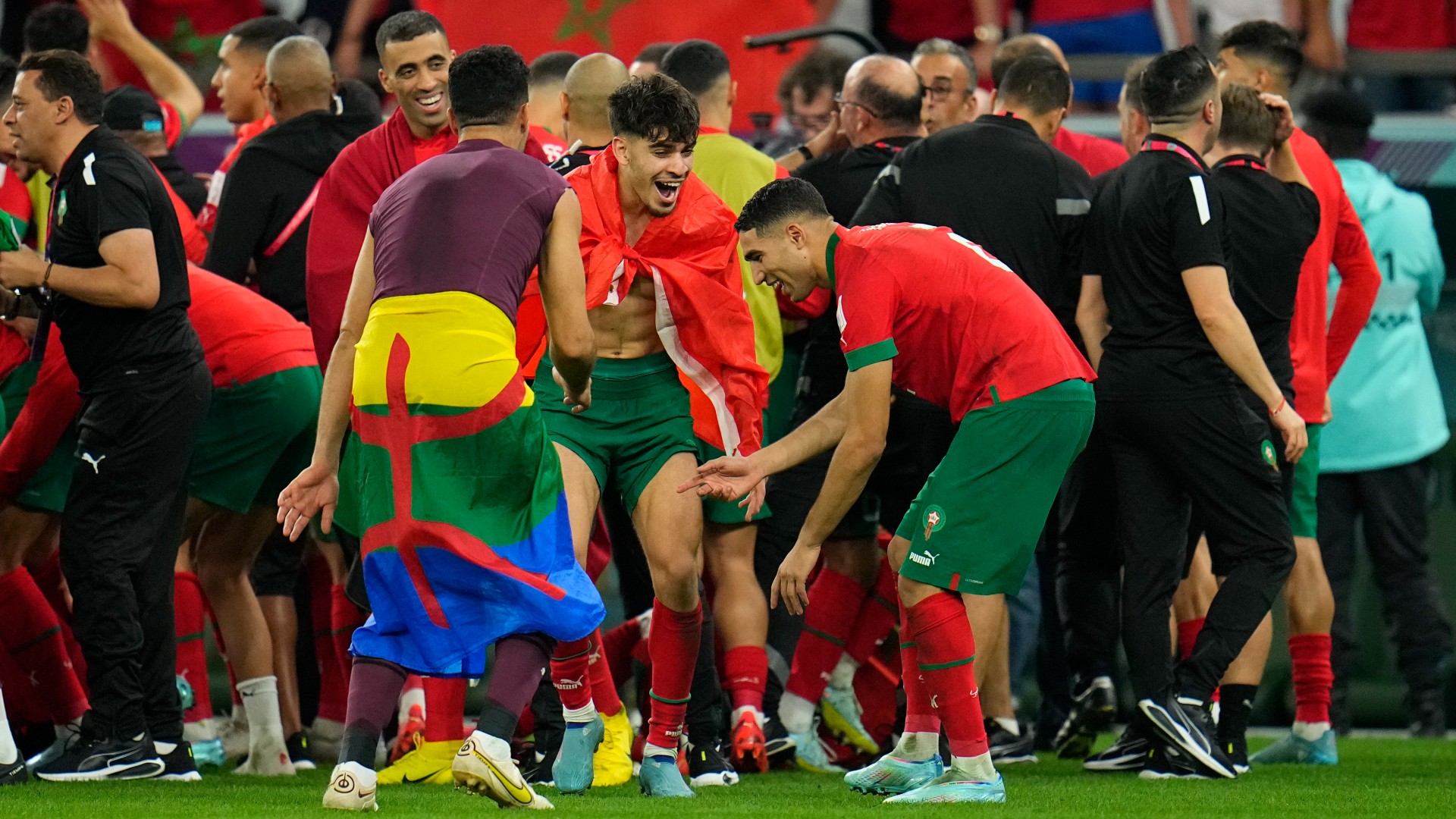 Morocco's reserve goalkeeper Munir Mohamedi can be seen with Amazigh flag wrapped around his waist as the Moroccan players celebrate their win against Spain at the Education City Stadium in Al Rayyan, on 6 December 2022 (Associated Press)