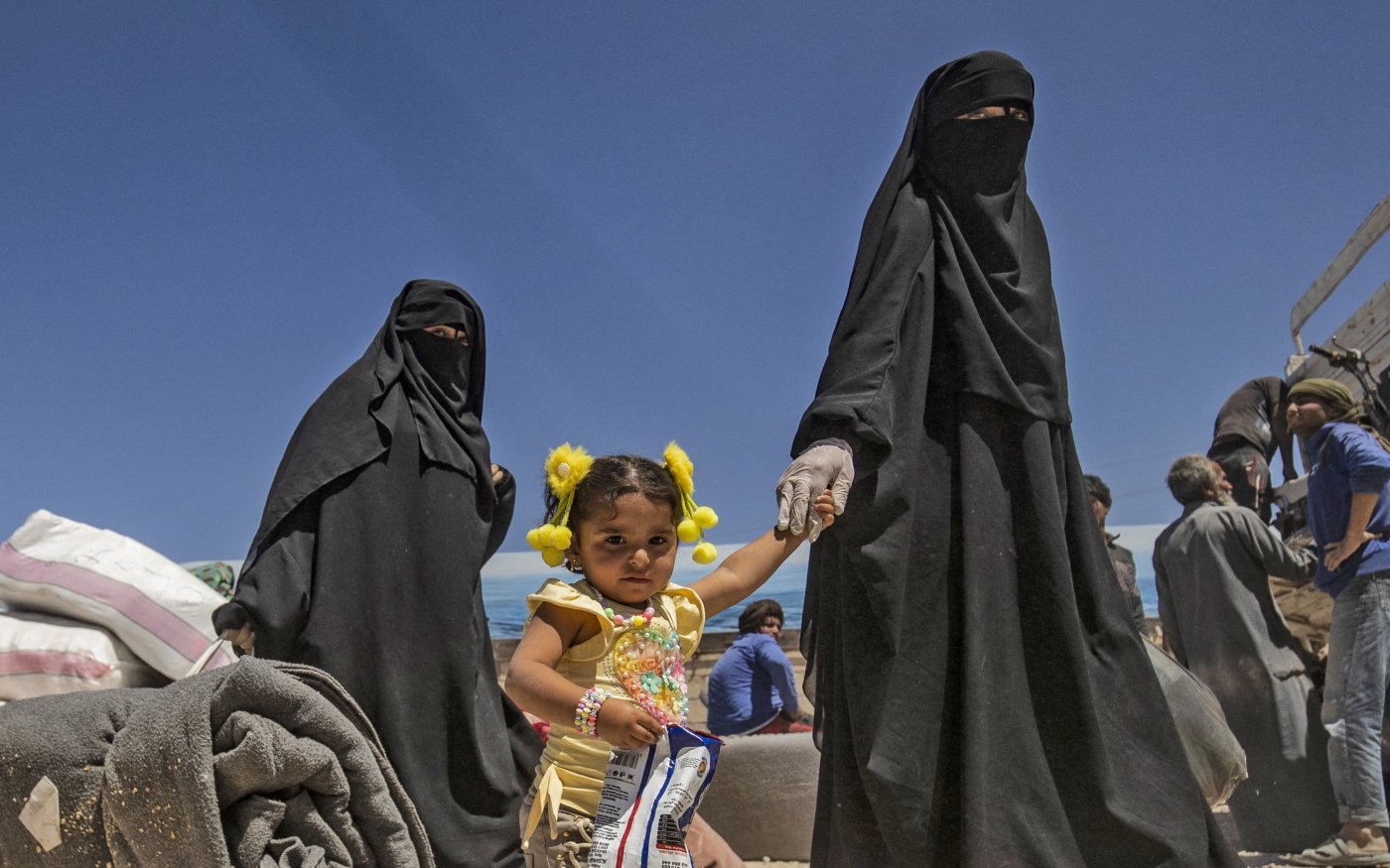 Des femmes marchent avec des enfants et des effets personnels lors de la libération d’un groupe de familles syriennes du camp d’al-Hol administré par les Kurdes, le 11 mai 2021 (AFP)