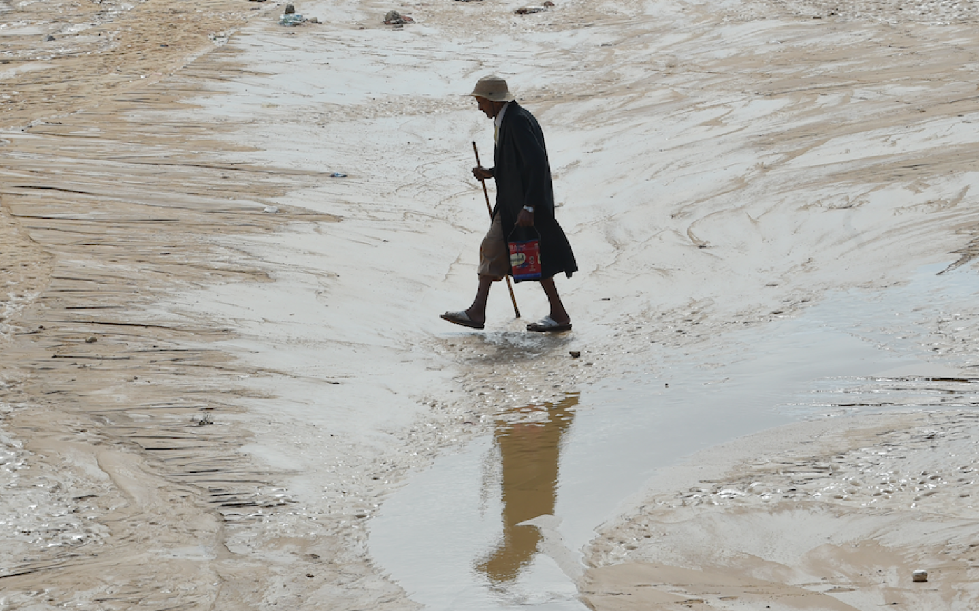 Un homme marche sur une route inondée dans le gouvernorat côtier tunisien de Nabeul (AFP)