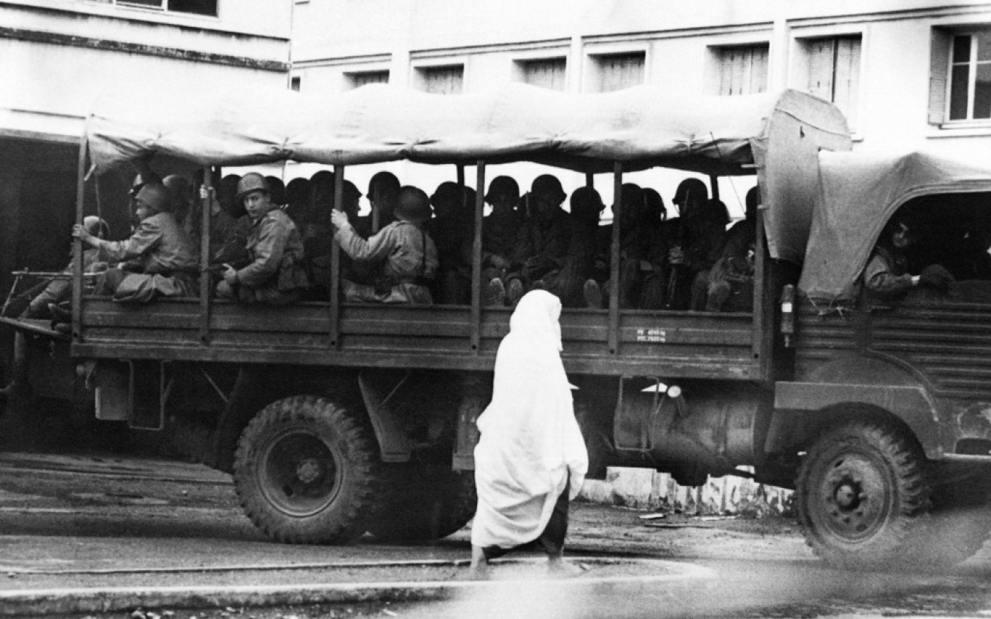 Une femme musulmane passe devant un camion de l’armée française avec des soldats patrouillant dans les rues de Bab El Oued, le 23 mars 1962, alors que l’armée française a fermé le quartier pour trouver des partisans de l’OAS (AFP)