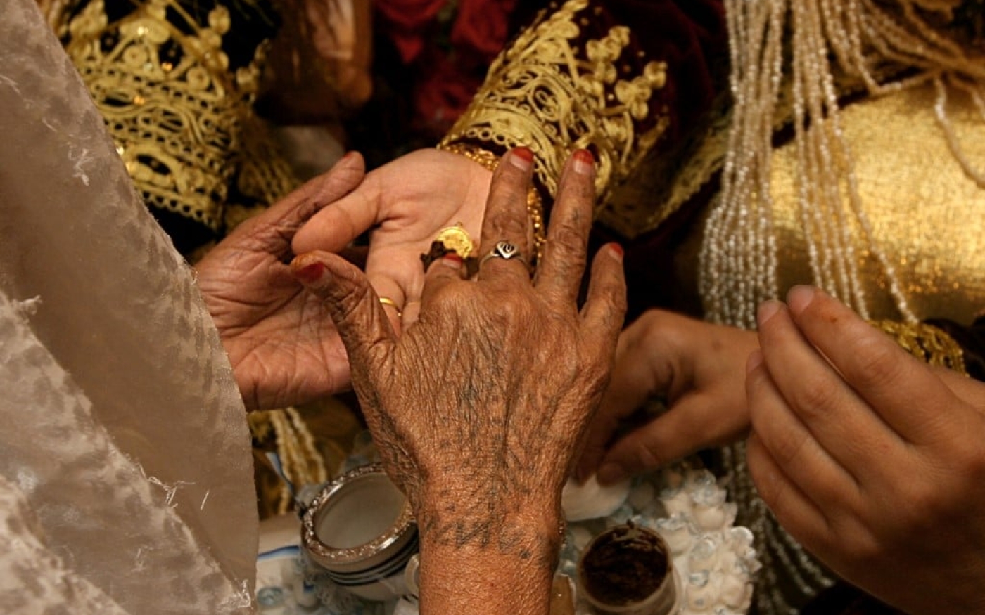 Des Algériennes décorent les mains d’une mariée avec du henné lors de sa cérémonie de mariage (AFP)