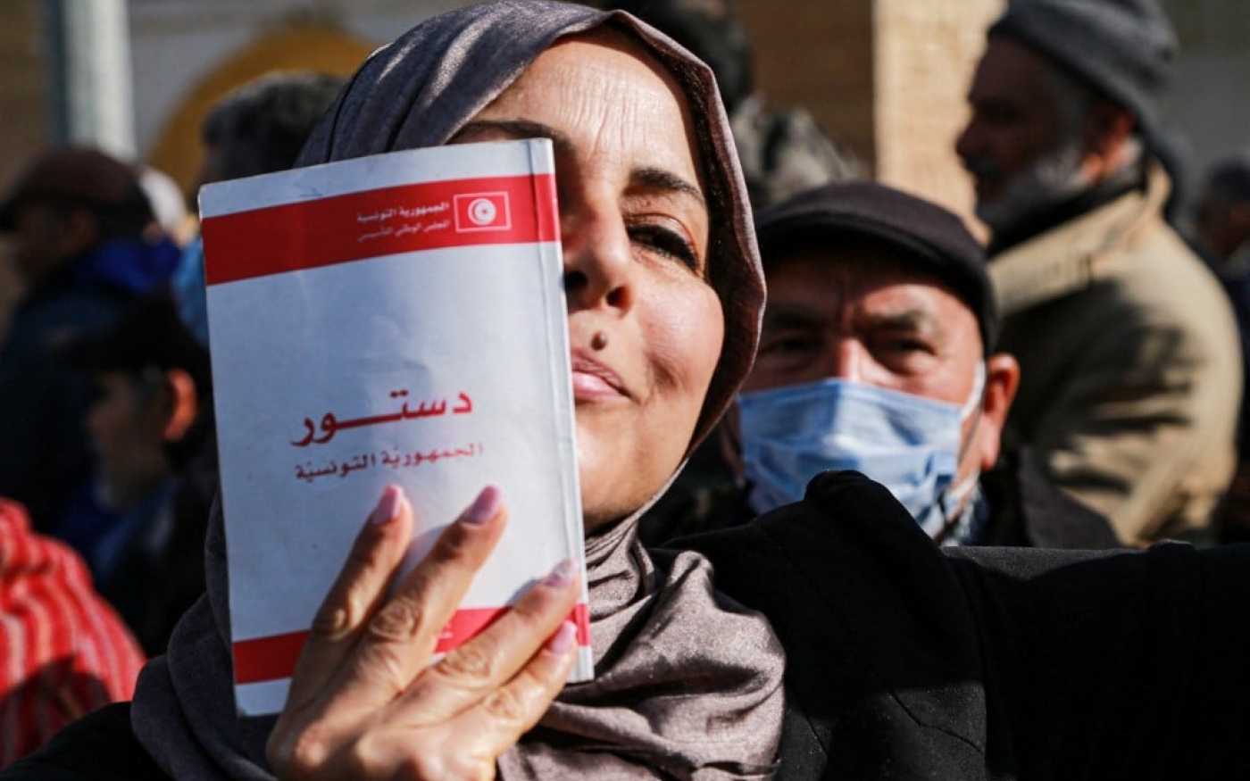 Une Tunisienne montre une copie de la Constitution, pendant une manifestation à l’appel du parti islamoconservateur Ennahdha, à Tunis, le 13 février 2022 (AFP/Anis Mili)