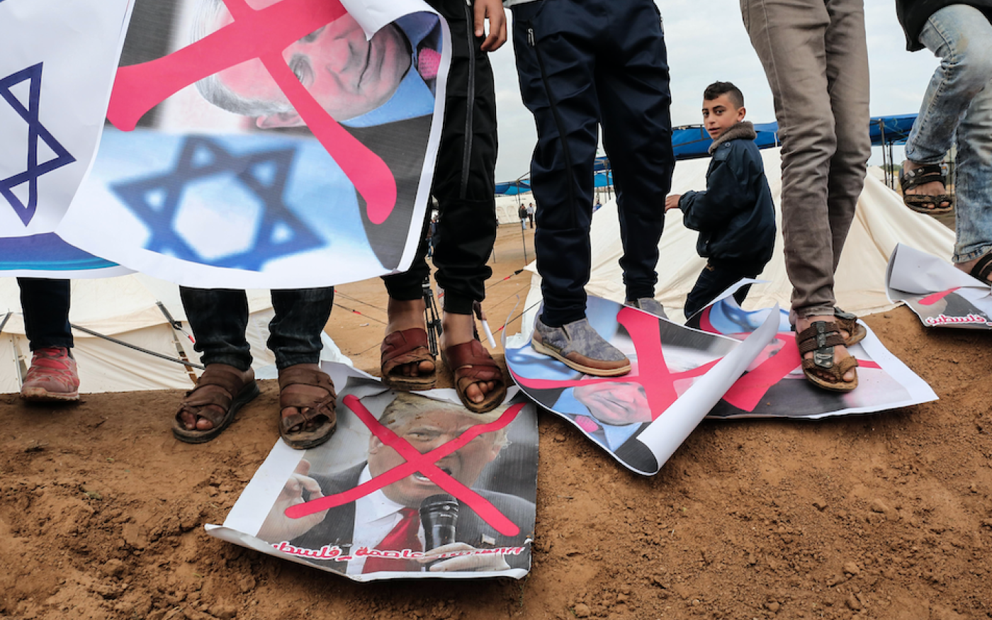Des Palestiniens marchent sur des affiches représentant le premier ministre israélien Benjamin Netanyahu et le président américain Donald Trump, lors d’une manifestation, à Gaza, le 30 mars 2018 (AFP)