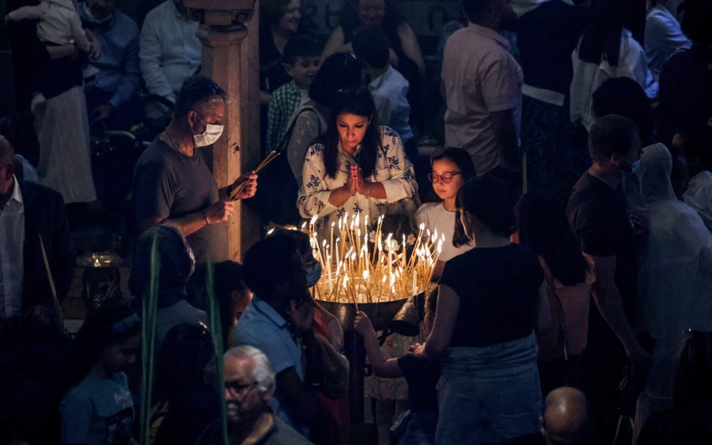 Des fidèles chrétiens allument des cierges et prient lors des célébrations du dimanche des Rameaux à l’église du Saint-Sépulcre à Jérusalem (AFP)