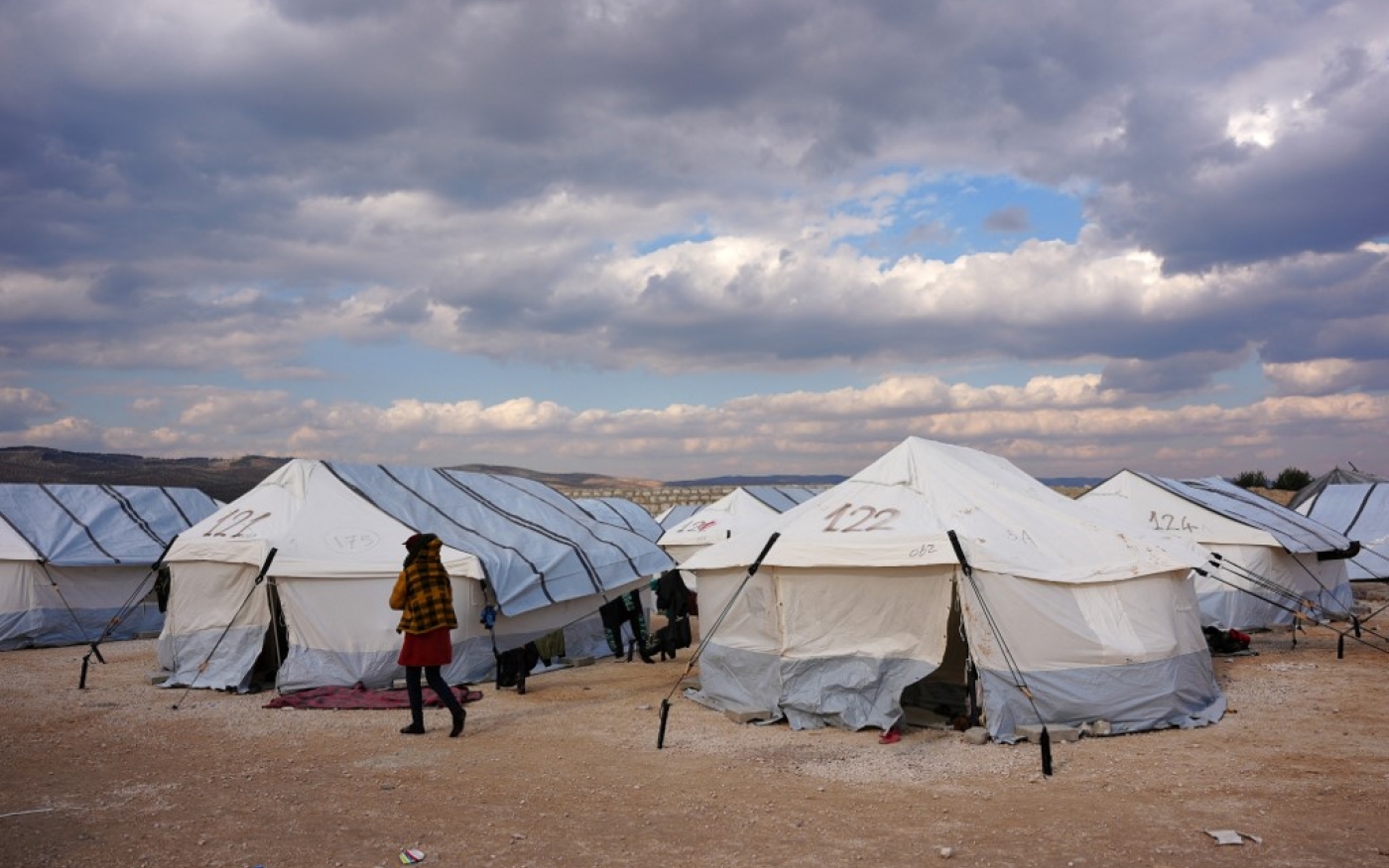 Un Syrien, déplacé à la suite du tremblement de terre meurtrier qui a frappé la Turquie et la Syrie, passe devant des tentes dans un camp temporaire, dans la campagne de Jandairis, dans le nord-ouest de la Syrie, le 11 février 2023 (AFP/Rami al-Sayed)