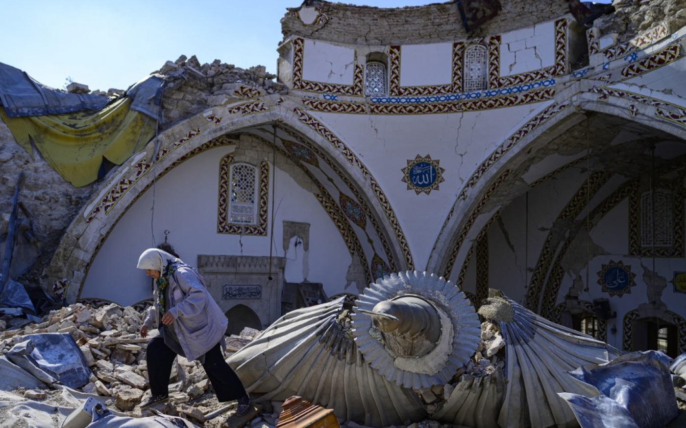 Sur cette photo prise le 12 février 2023, une femme passe devant la mosquée Habib’i Neccar détruite dans la ville historique d’Antakya, au sud de Hatay (AFP/Yasin Akgul)