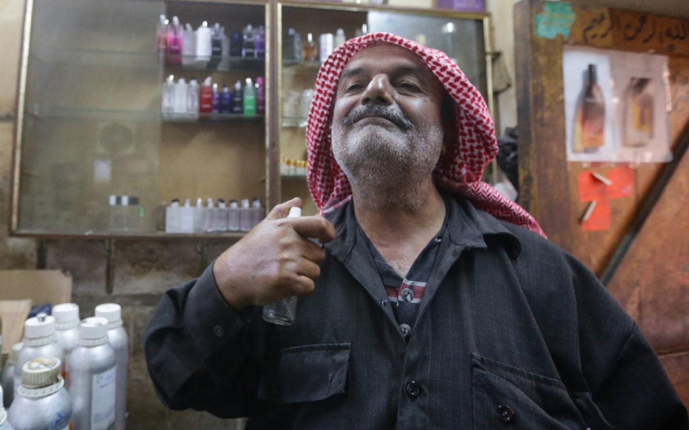Ahmad Dorra, venu acheter du parfum pour sa famille, essaie un parfum fabriqué par le parfumeur syrien Mohammad al-Masri dans sa boutique d’un souk historique de la vieille ville de Damas le 31 octobre 2022. (AFP/Louai Beshara)