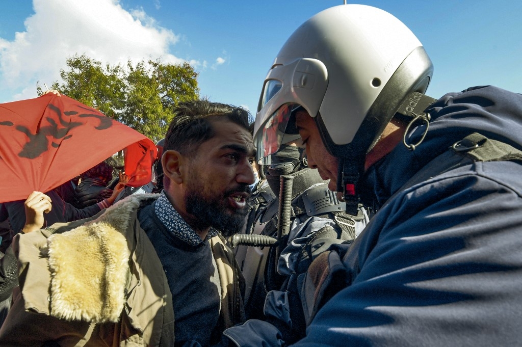 Face-à-face entre un manifestant et un policier, à Ettadhamen, le 26 janvier 2021 (AFP)