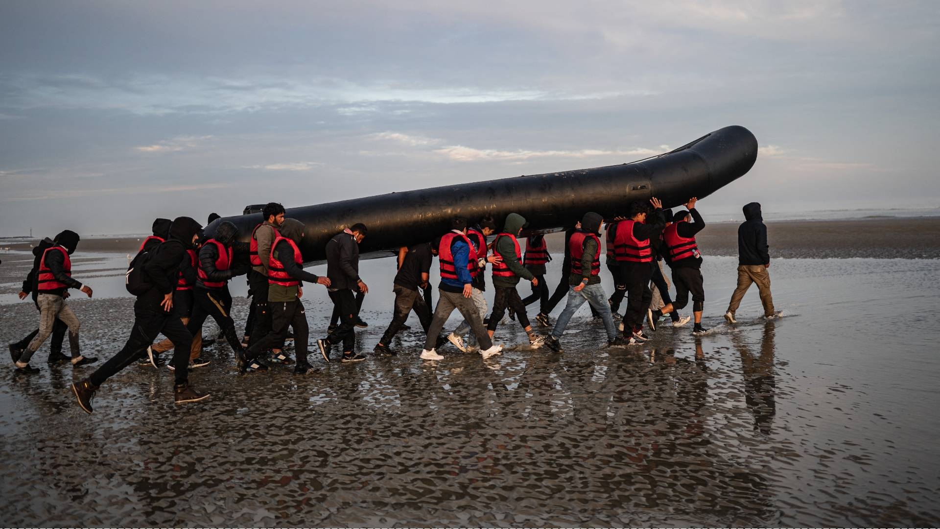 People carry a boat on their shoulders as they prepare to embark on the beach of Gravelines, near Dunkirk, northern France on 12 October 2022 in an attempt to cross the English Channel (AFP)
