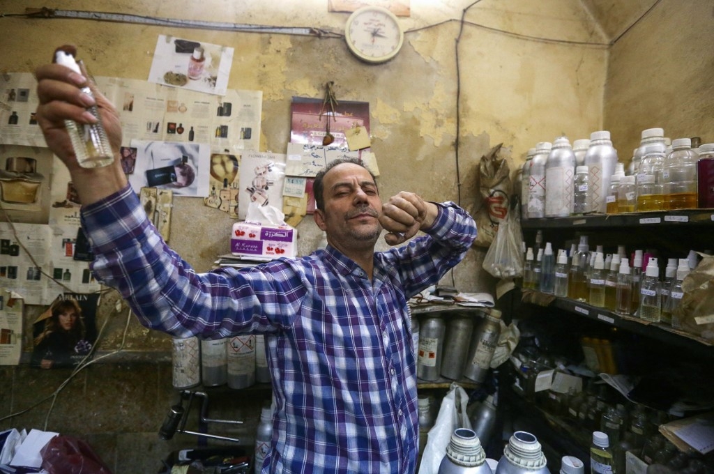 Le parfumeur syrien Mohammad al-Masri vaporise l’une de ses créations dans sa boutique, dans la vieille ville de Damas, le 31 octobre 2022 (AFP/Louai Beshara)