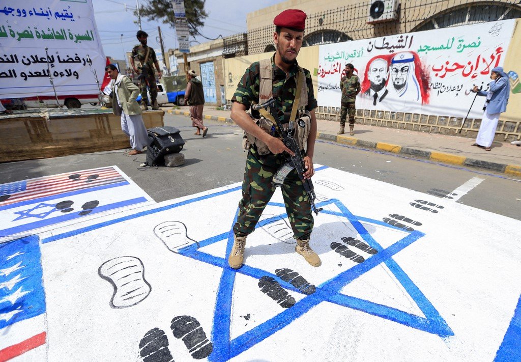 Un combattant houthi piétine les drapeaux américains et israéliens lors d’un rassemblement à Sanaa pour protester contre l’accord négocié par les Américains pour normaliser les relations israéliennes avec les Émirats (AFP)